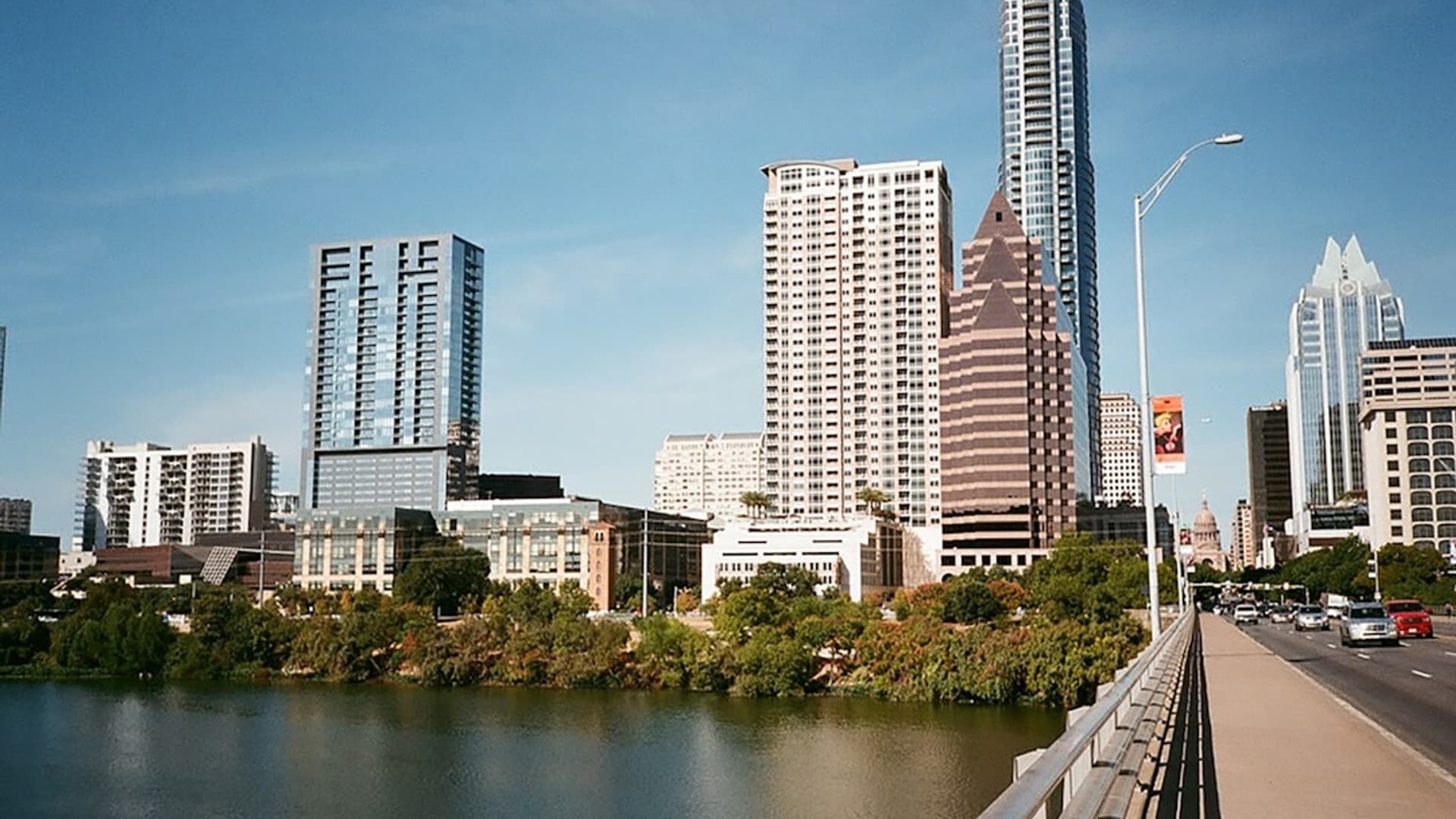 View of Downtown Austin - Urban Living in the Heart of Texas Austin skyline at dusk featuring the Frost Bank Tower and Lady Bird Lake, warm sunset colors reflecting on the water